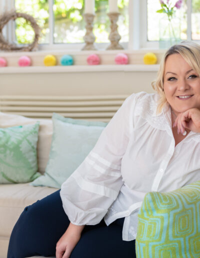 a woman poses on a sofa for a portrait during a personal brand photo shoot in surrey