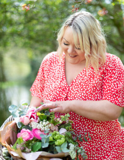 a woman inspects a bunch of flowers in her basket in her garden