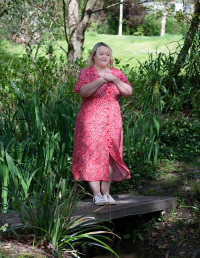 a woman stands in a garden doing some breath work
