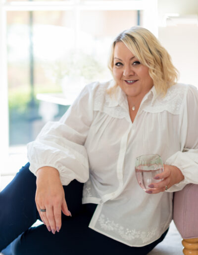 a woman leans against a chair during a personal brand photo shoot in surrey