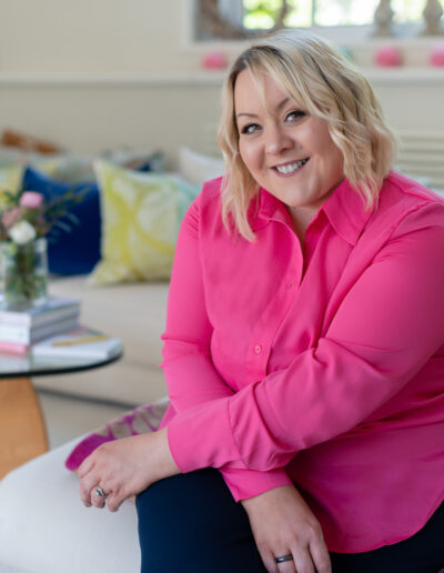 a woman in a pink shirt smiles for the camera during a personal brand photo shoot in surrey