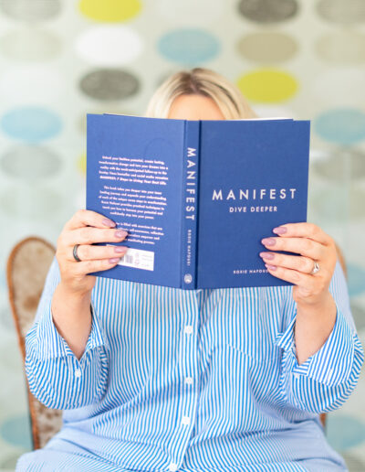 a woman holds a manifesting book in front of her during a personal brand photo shoot in surrey
