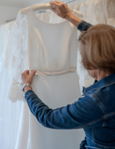 a bridal designer looks at the waistband of a wedding gown in her design studio