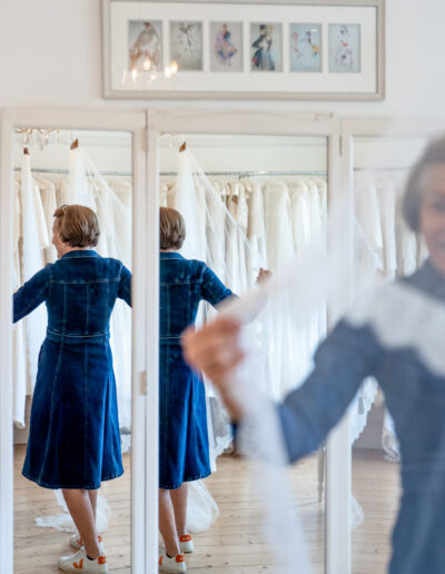 a bridal designer plays with a wedding veil in her studio