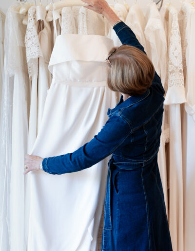 a bridal designer holds up one of her wedding gowns in her studio