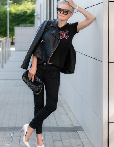 a woman wearing rock chick clothing leans against a wall during a personal brand photo shoot
