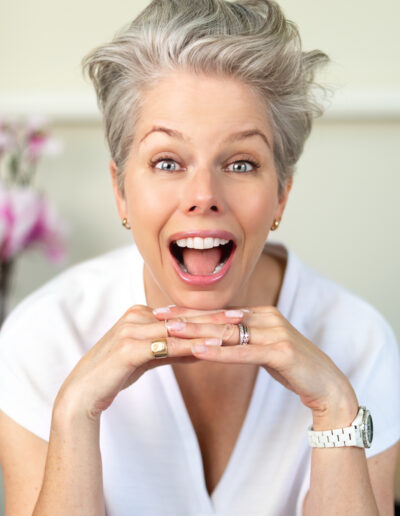 a silver haired woman laughs at the camera during a personal brand photo shoot in surrey
