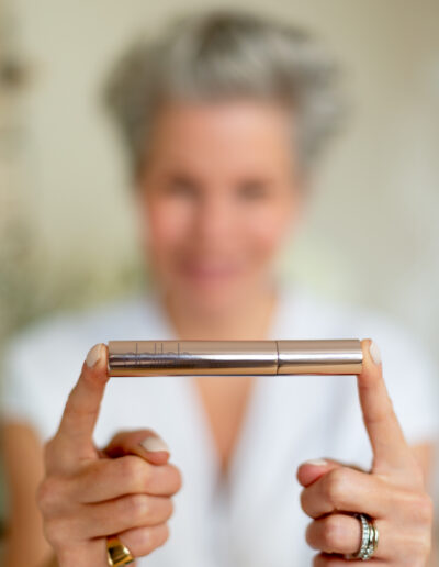 a woman holds a cosmetic brush in front of her during a personal brand photo shoot in surrey