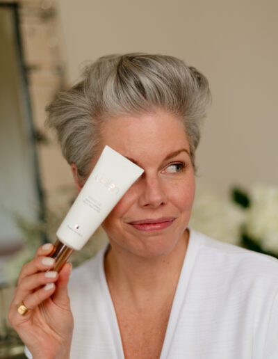 a woman holds up a skincare product during a personal brand photo shoot in surrey