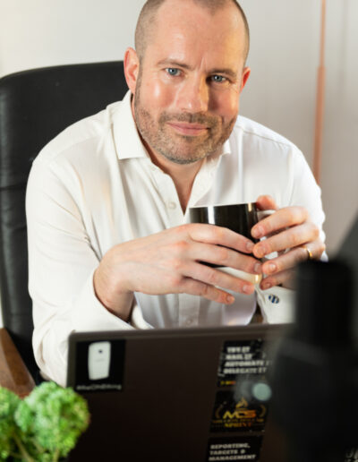 a man smiles over his computer during a personal brand photo shoot in surrey