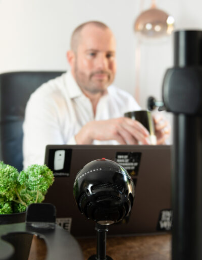 a man interacts via zoom with his podcast equipment during a personal brand photo shoot in surrey