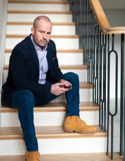 a man poses on the stairs during a personal brand photo shoot in surrey