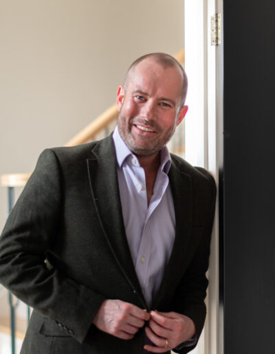 a man buttons up his jacket during a personal brand photo shoot in surrey